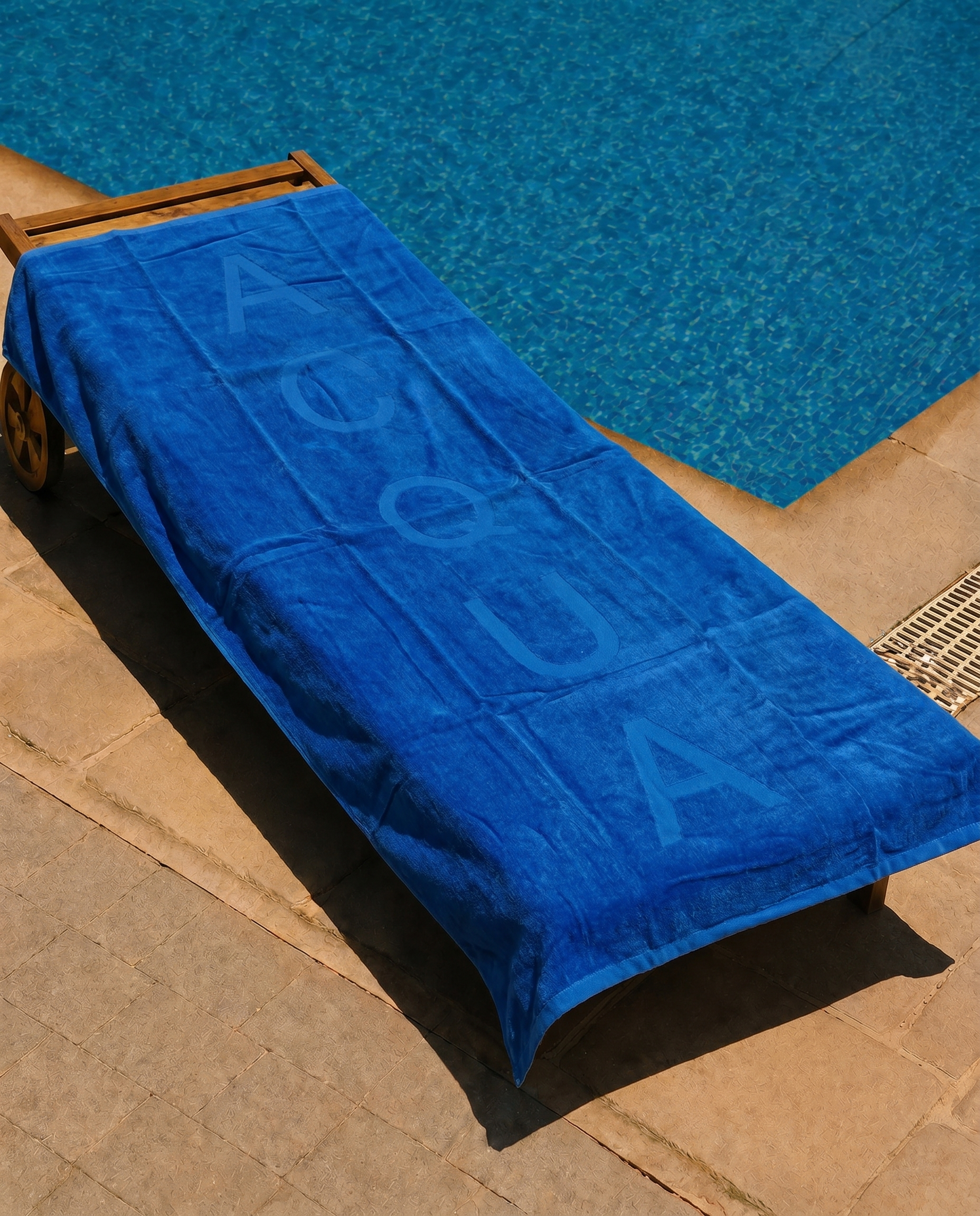 Acqua Blue Beach Towel draped over a lounge chair