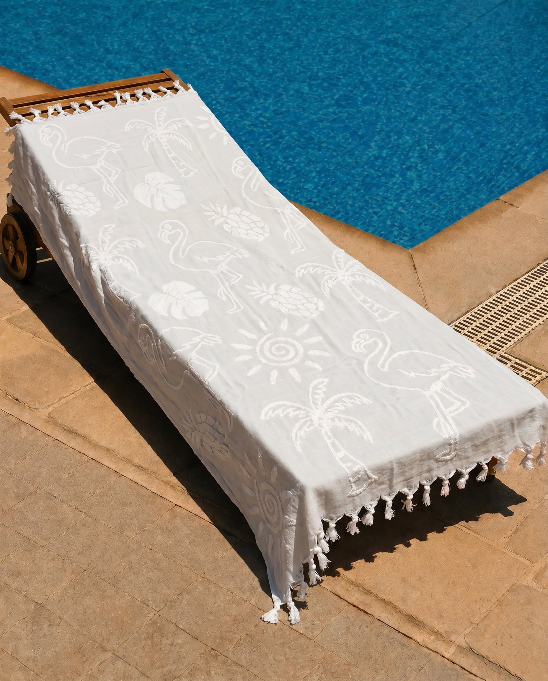 Ivory Flamingo Beach Towel draped over a lounge chair