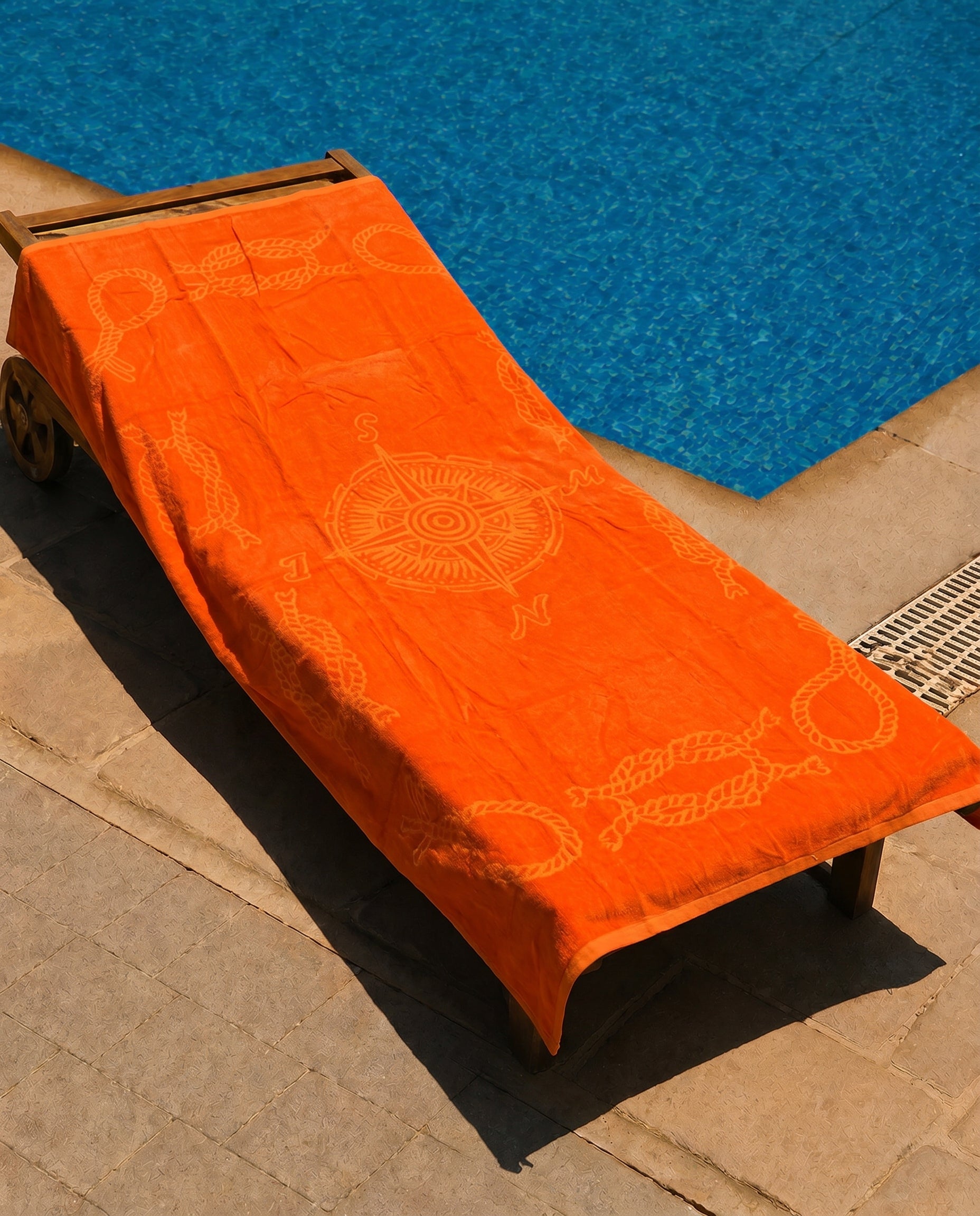 Marigold Compass Beach Towel draped over a lounge chair