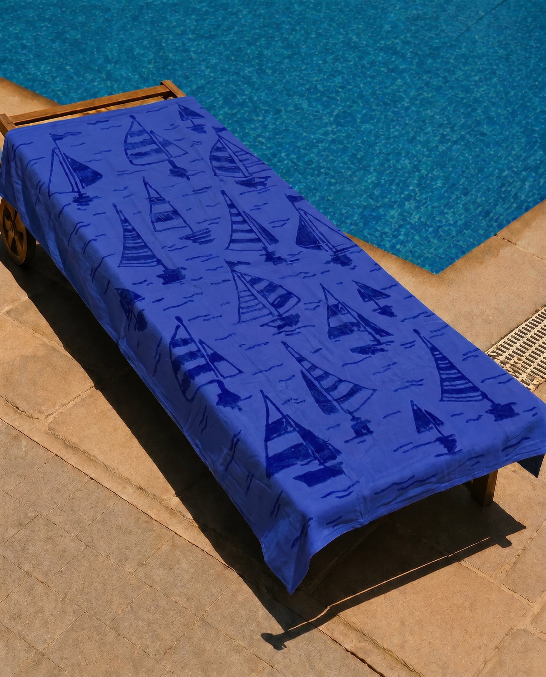 Azure Sailboat Beach Towel draped over a lounge chair