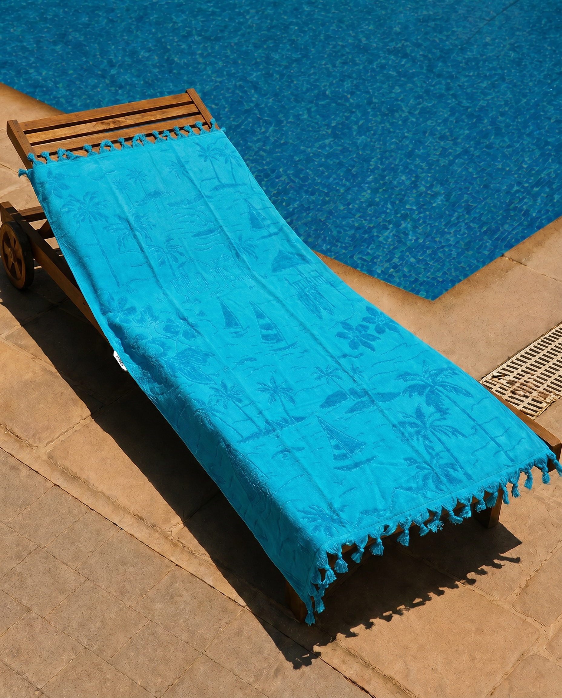 Turquoise Paradise Beach Towel draped over a lounge chair