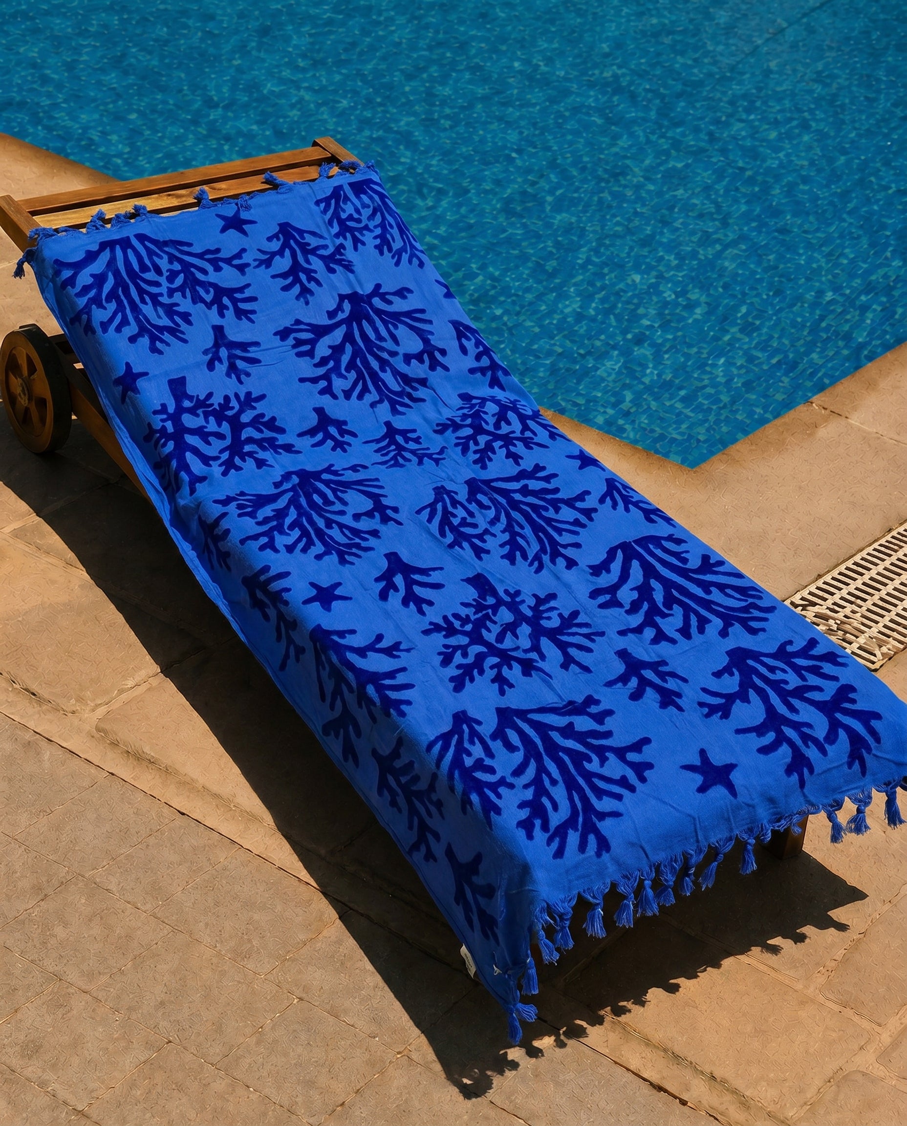 Cobalt Reef Beach Towel draped over a lounge chair