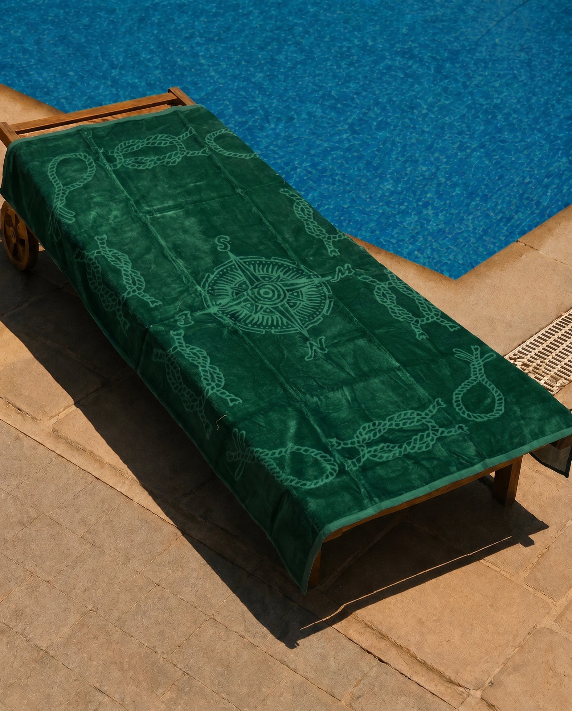 Emerald Compass Beach Towel draped over a lounge chair