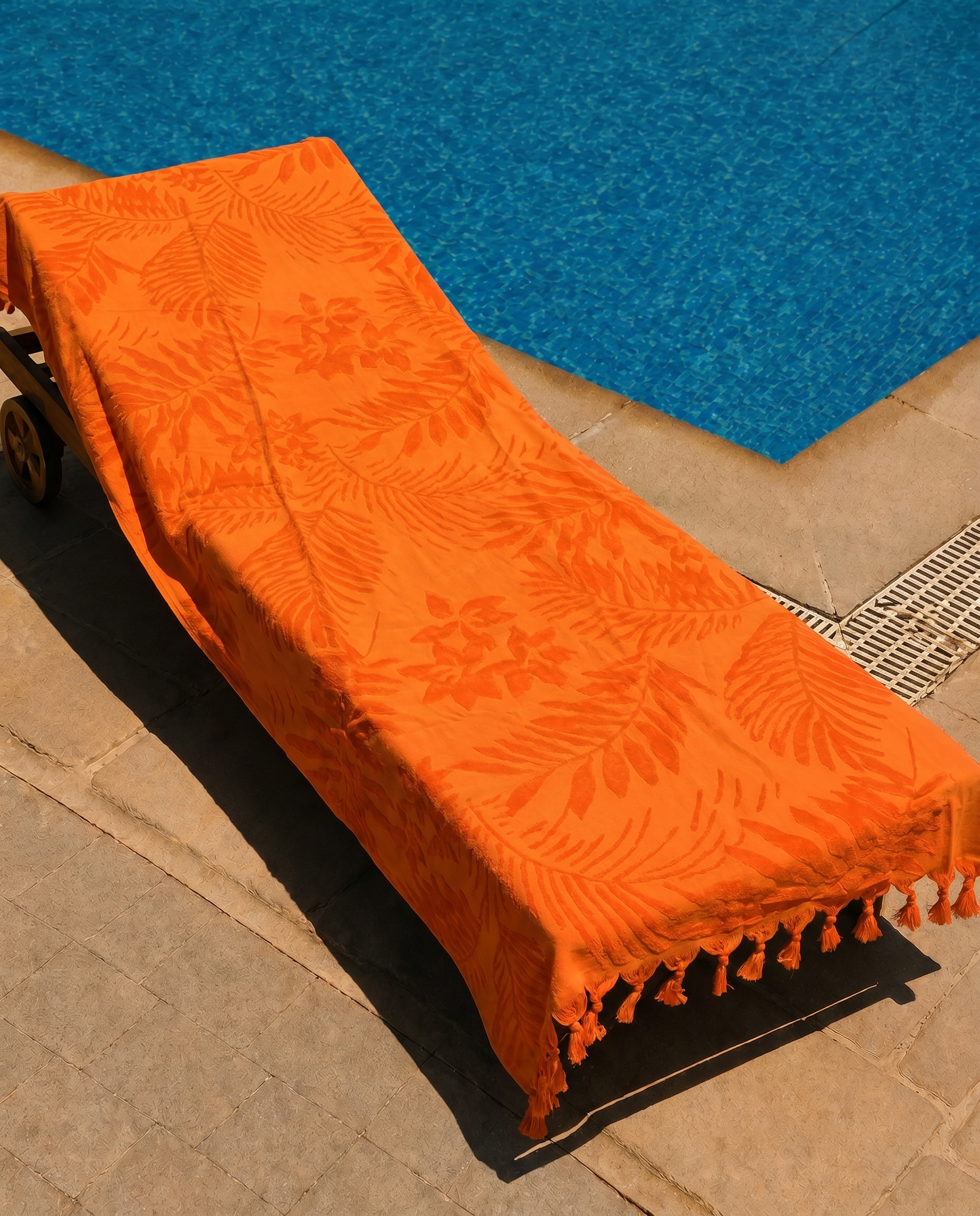 Tangerine Palm Beach Towel draped on a lounge chair