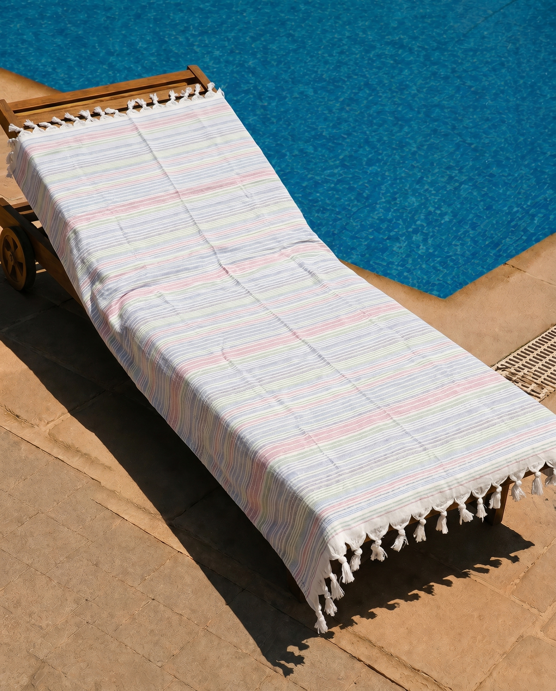 Pastel Stripe Beach Towel draped on a lounge chair