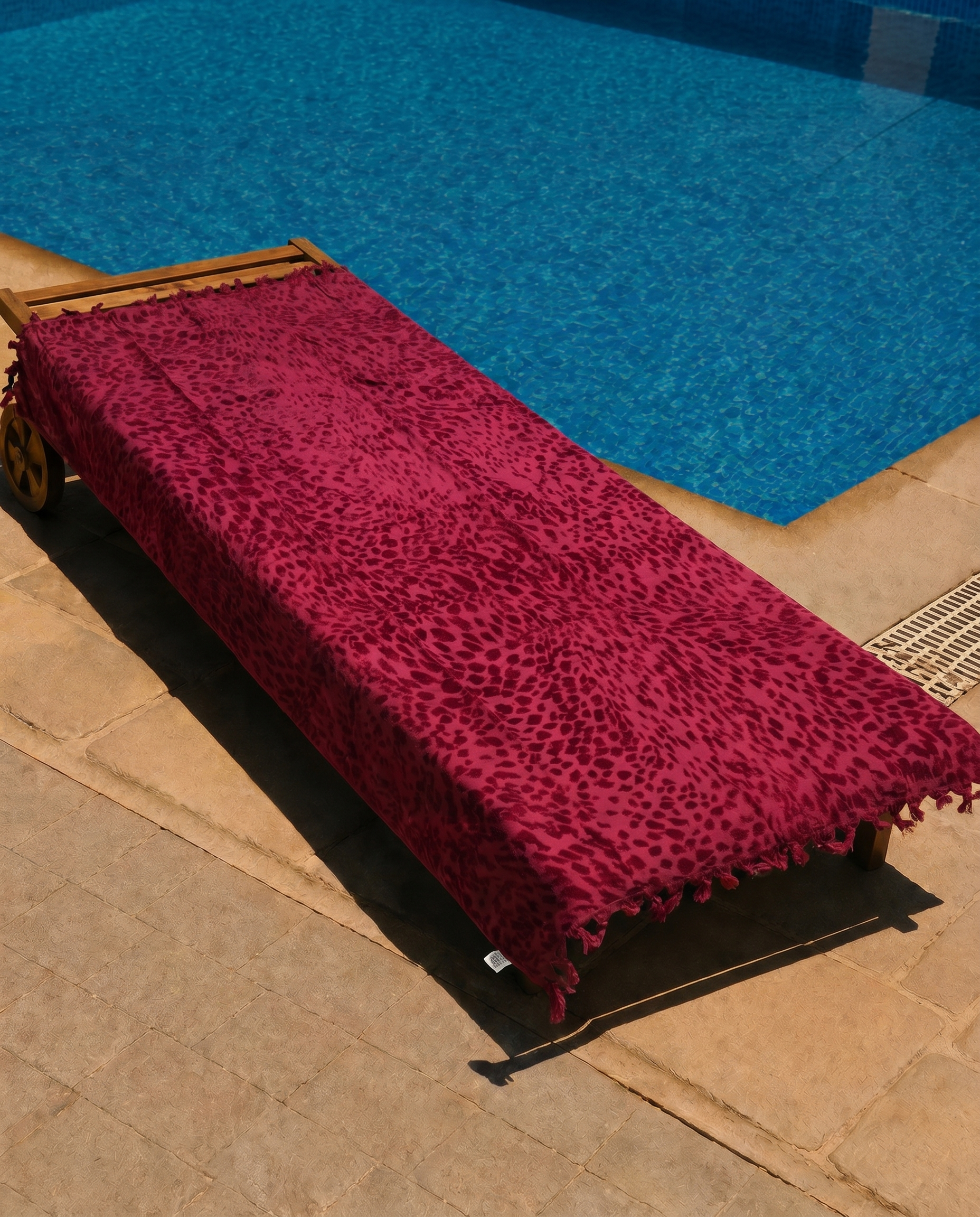 Crimson Leopard Beach Towel draped on a lounge chair