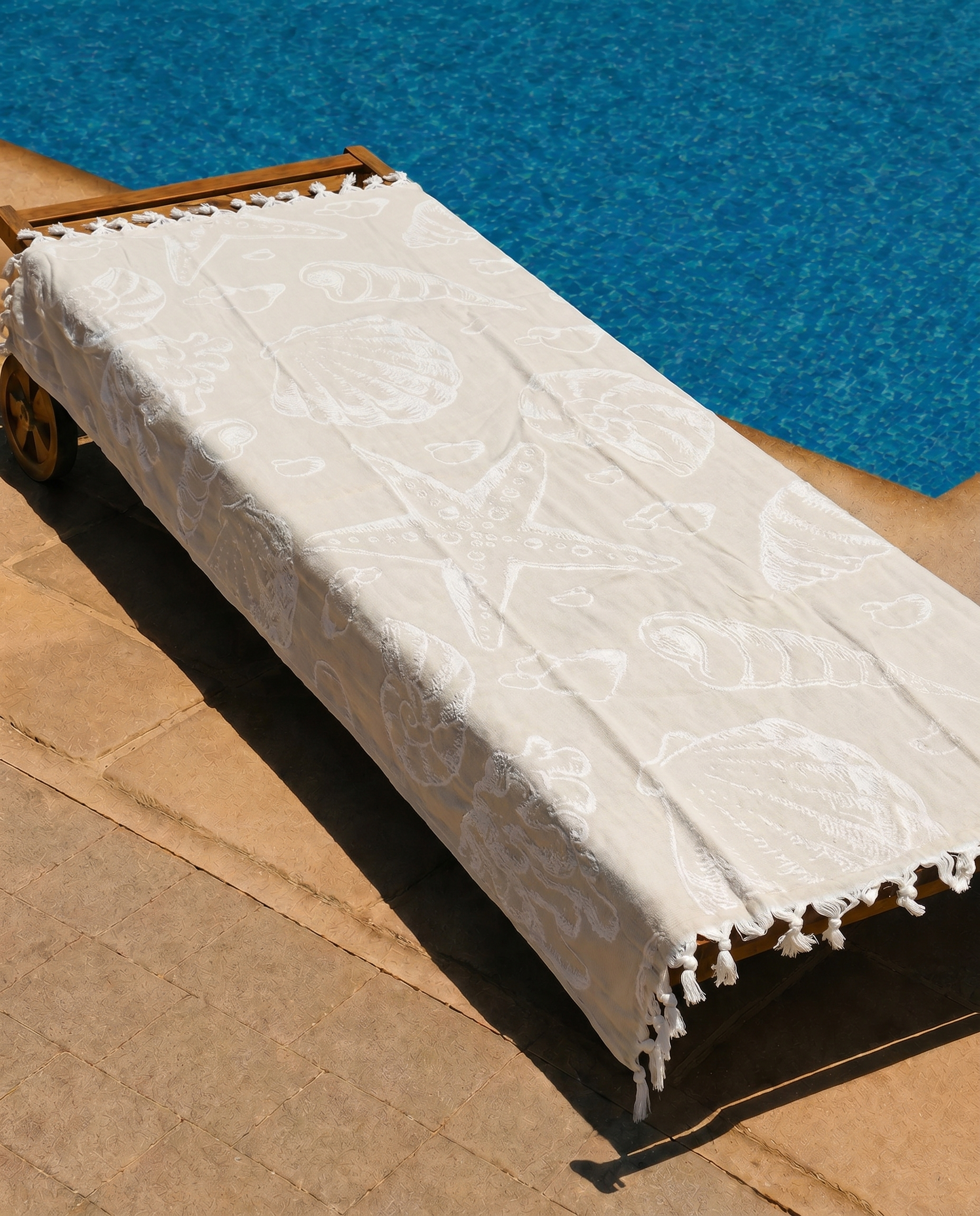 Ivory Shell Beach Towel draped on a lounge chair