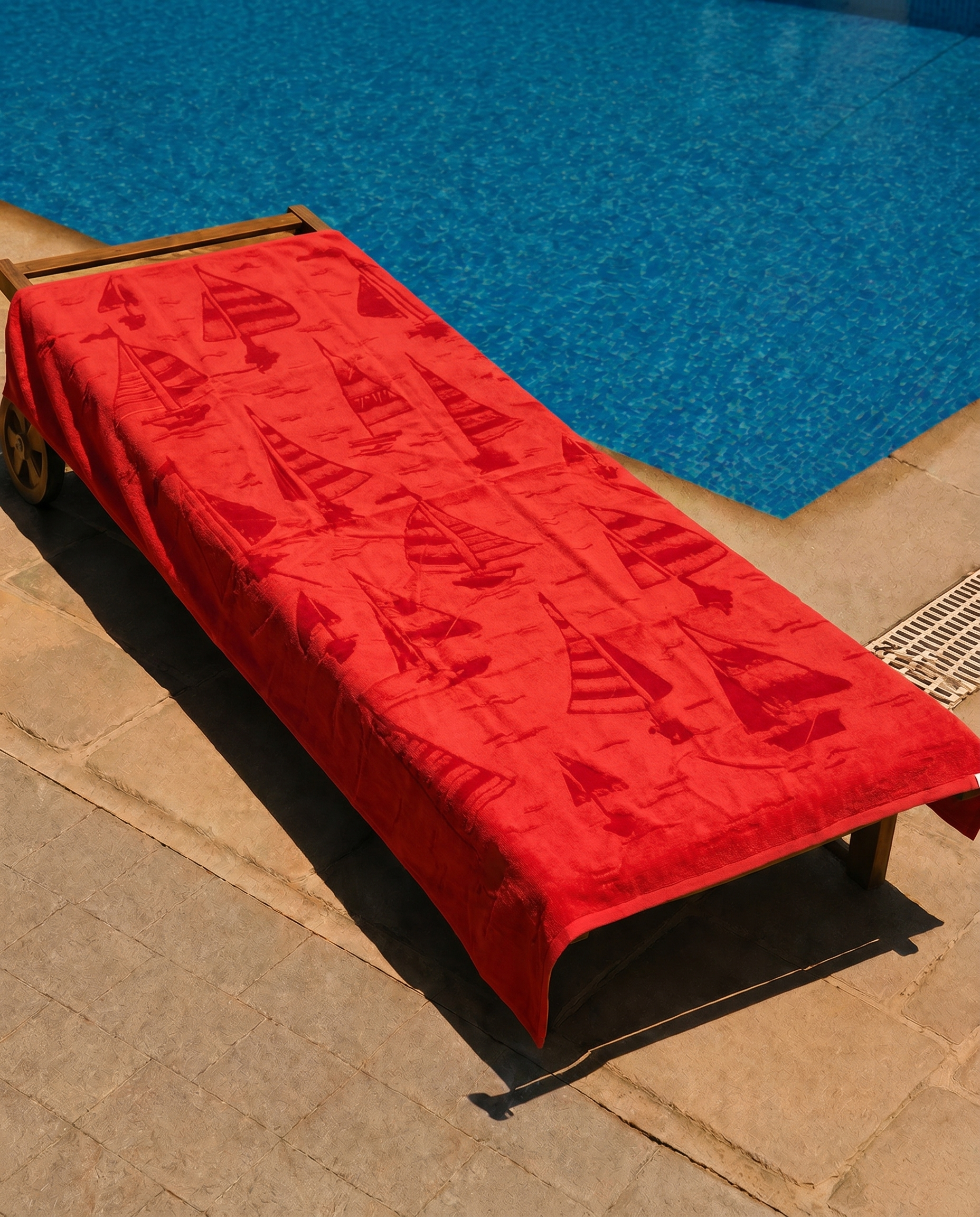 Scarlet Sailboat Beach Towel draped on a lounge chair