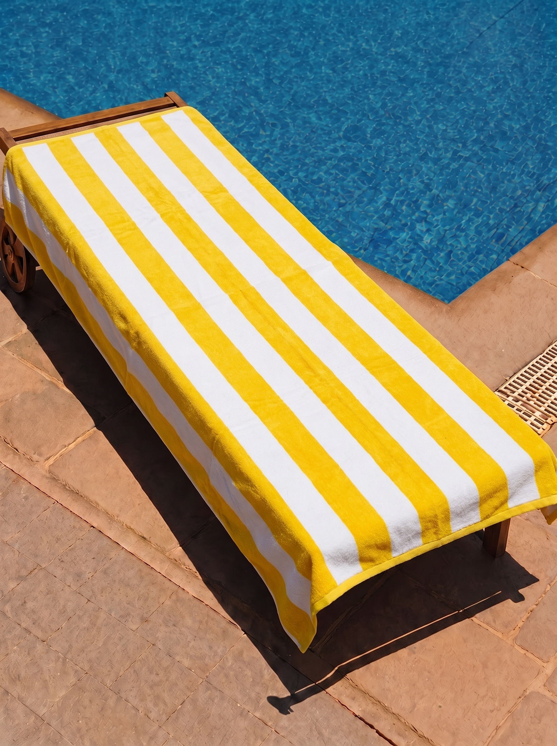 Yellow and white cabana stripe towel on a poolside lounge chair