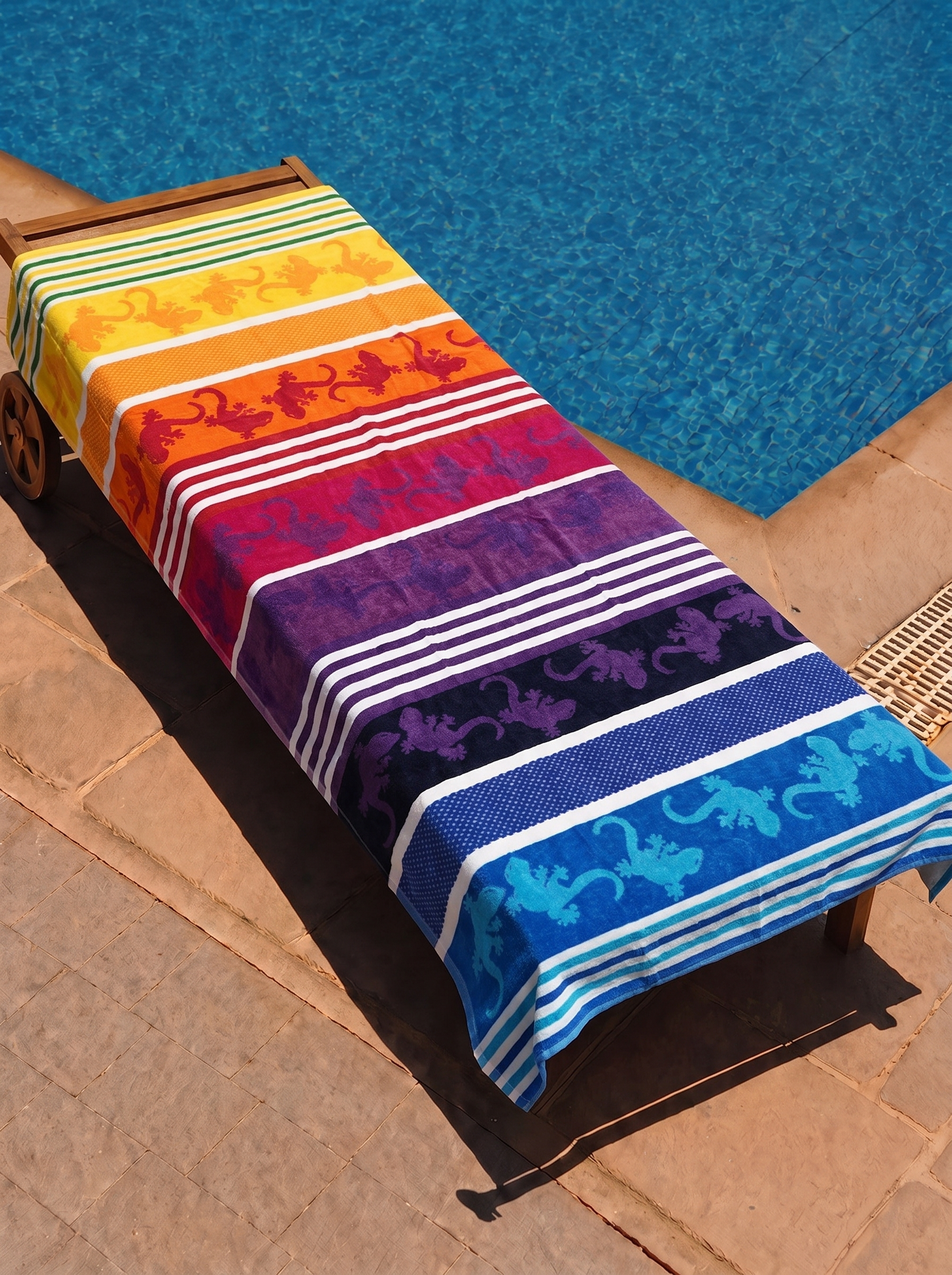 Rainbow gecko stripe towel on a poolside lounge chair