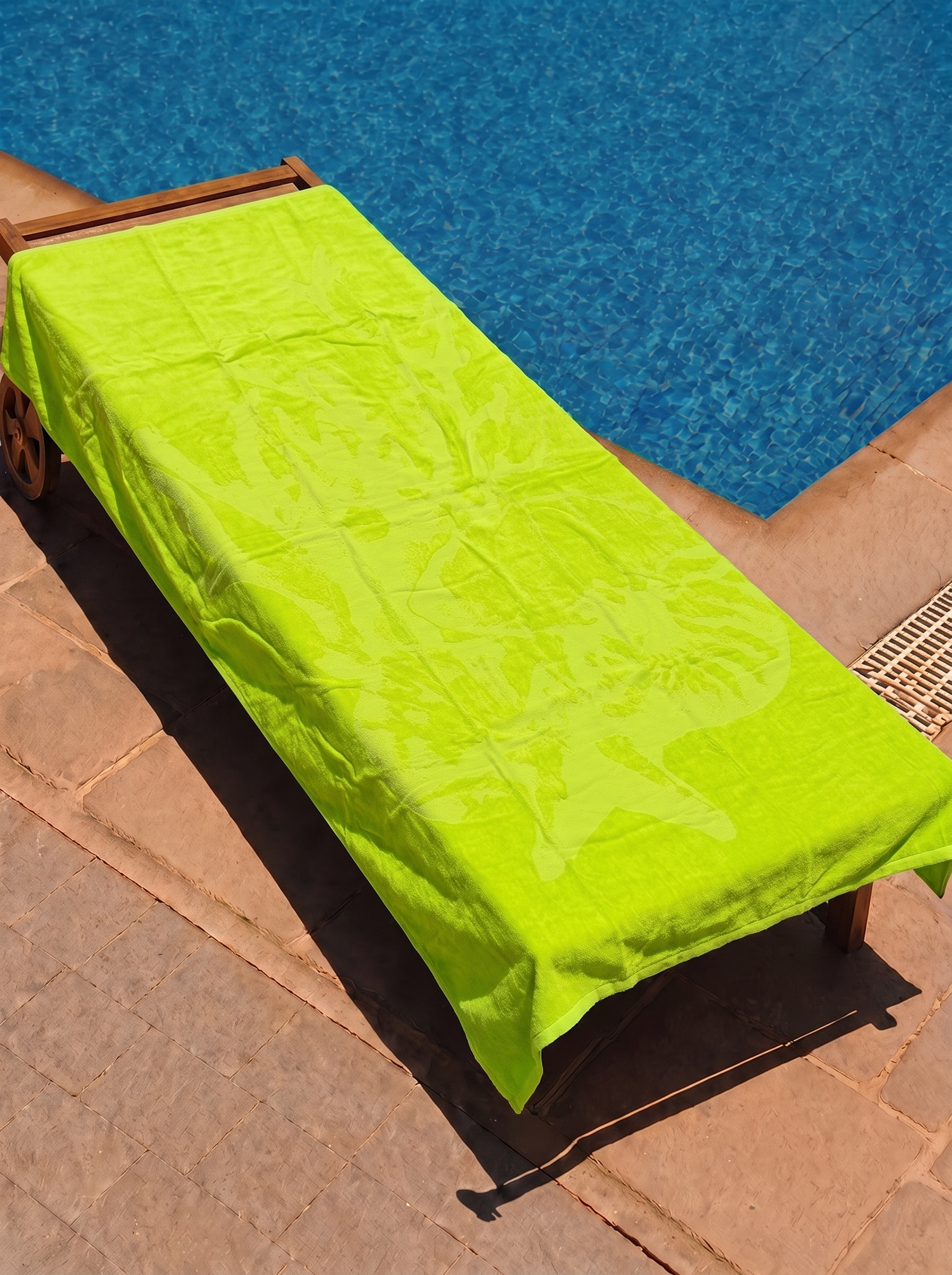 Neon yellow-green tonal coral towel on a poolside lounge chair
