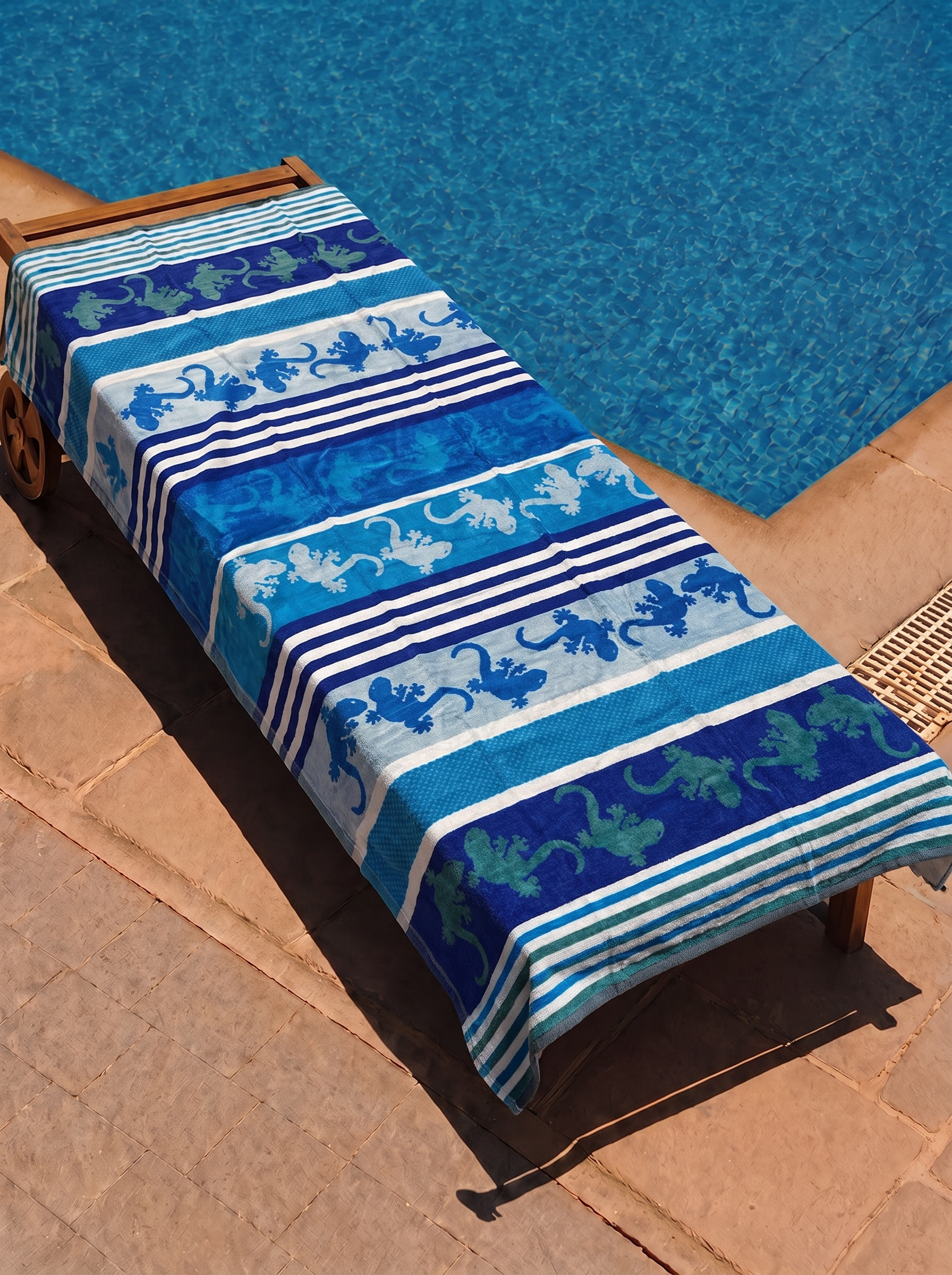 Blue and teal gecko stripe towel on a poolside lounge chair
