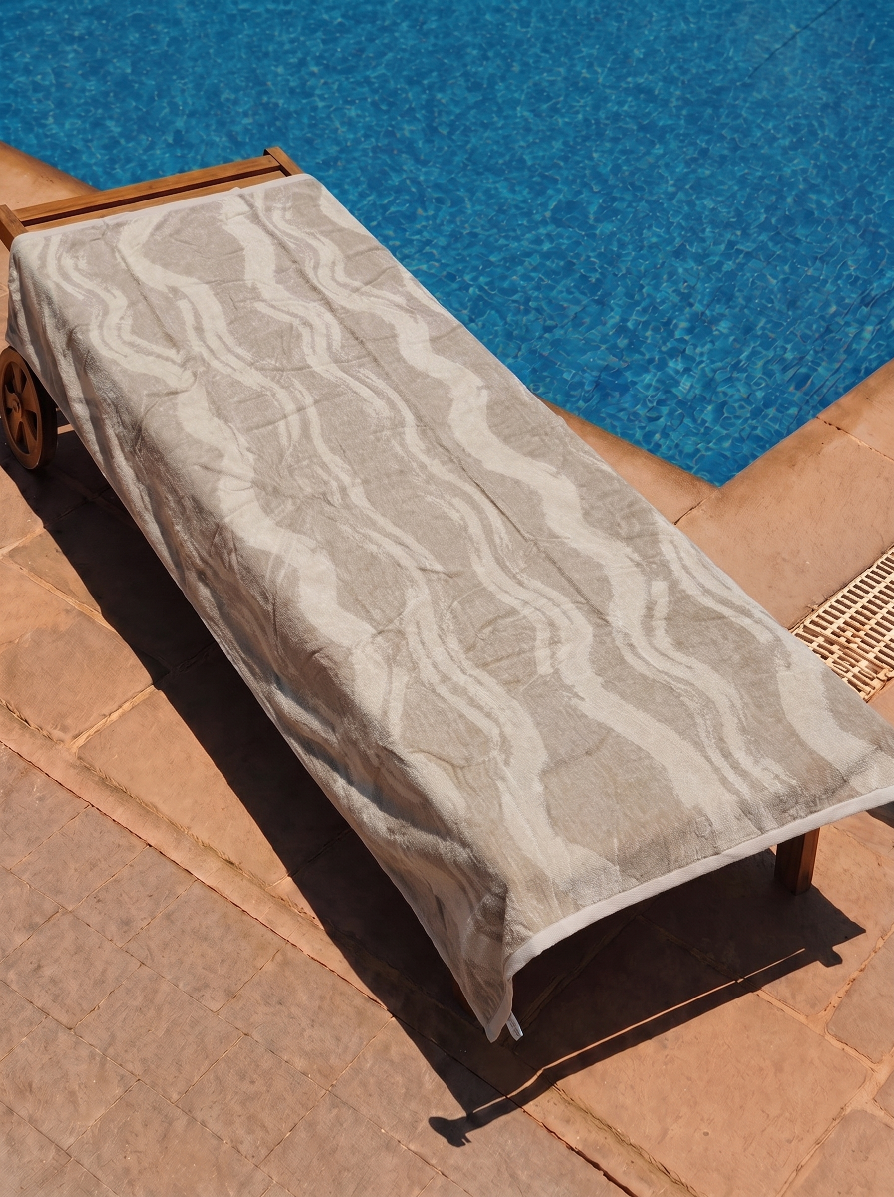 Beige tonal wavy stripe towel on a poolside lounge chair