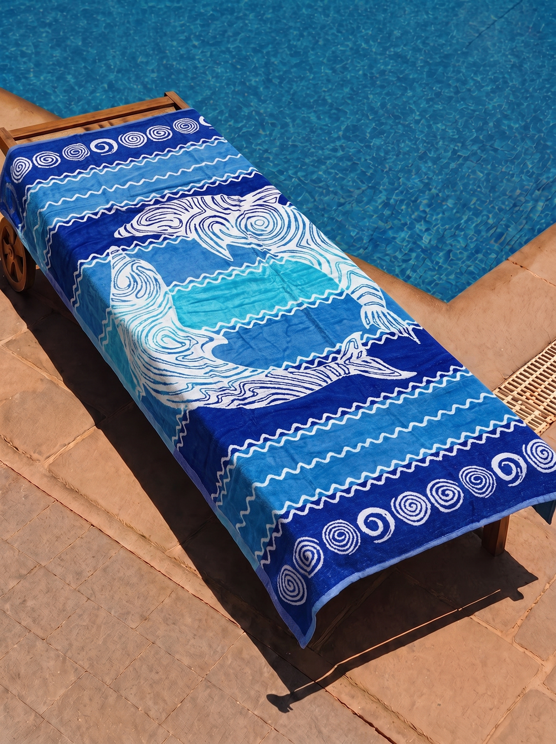 Blue dolphin swirl ombre towel on a poolside lounge chair