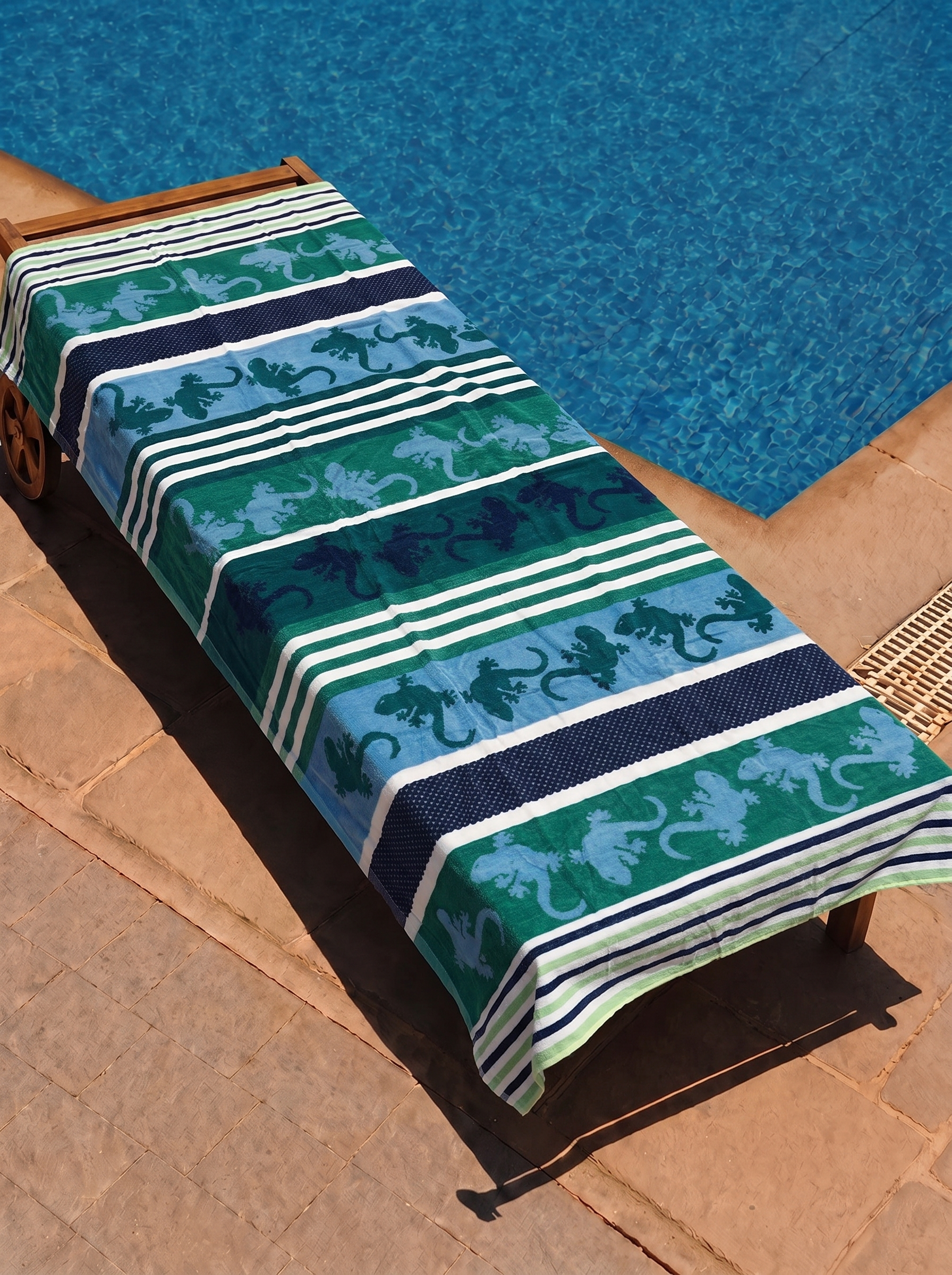 Green and blue gecko stripe towel on a poolside lounge chair