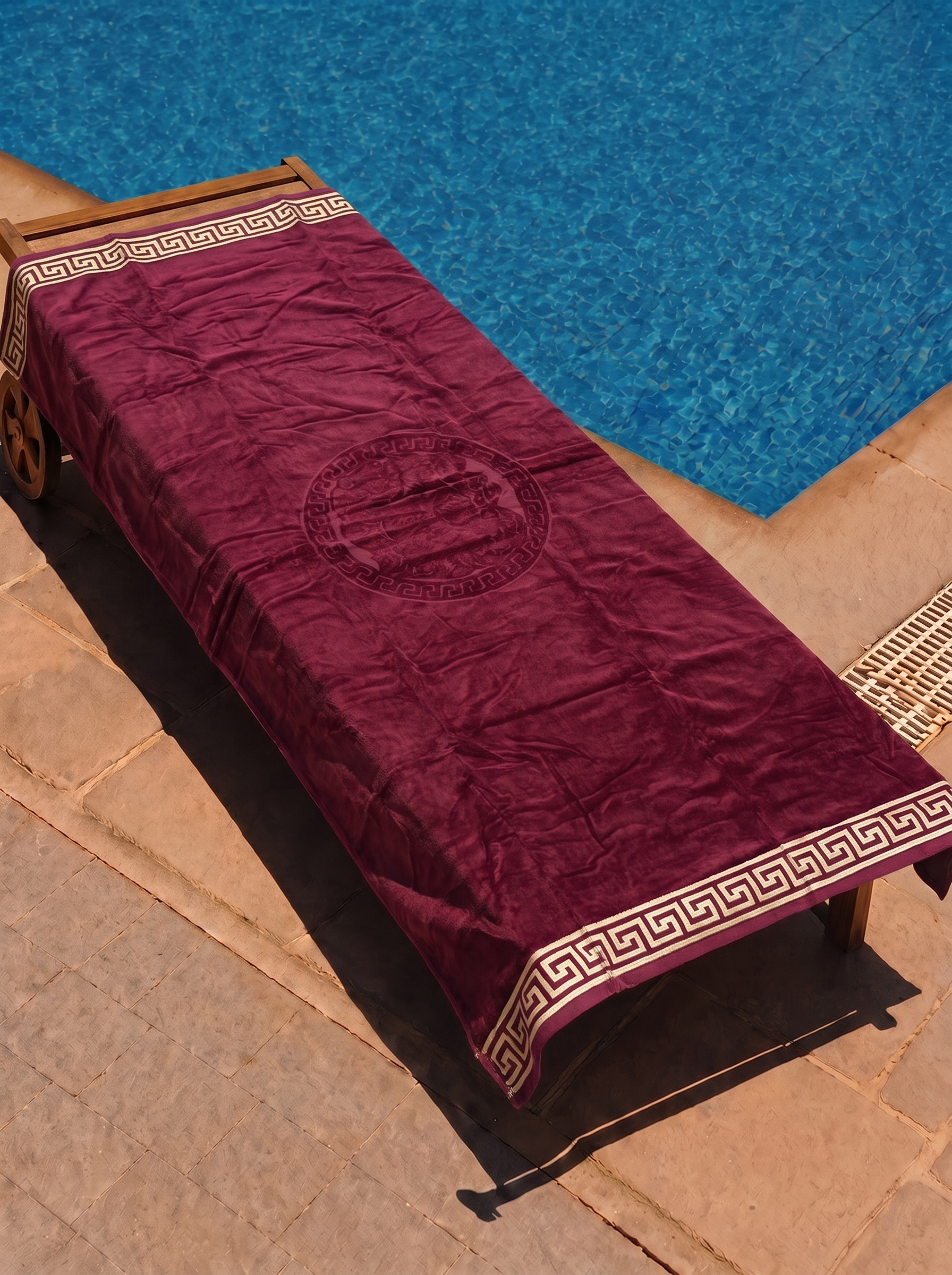 Burgundy Greek-key medallion towel on a poolside lounge chair