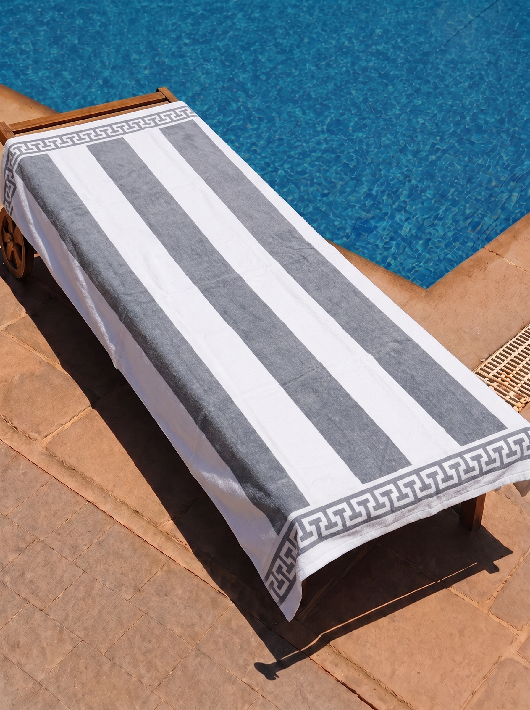 Grey and white Greek-key cabana towel on a poolside lounge chair