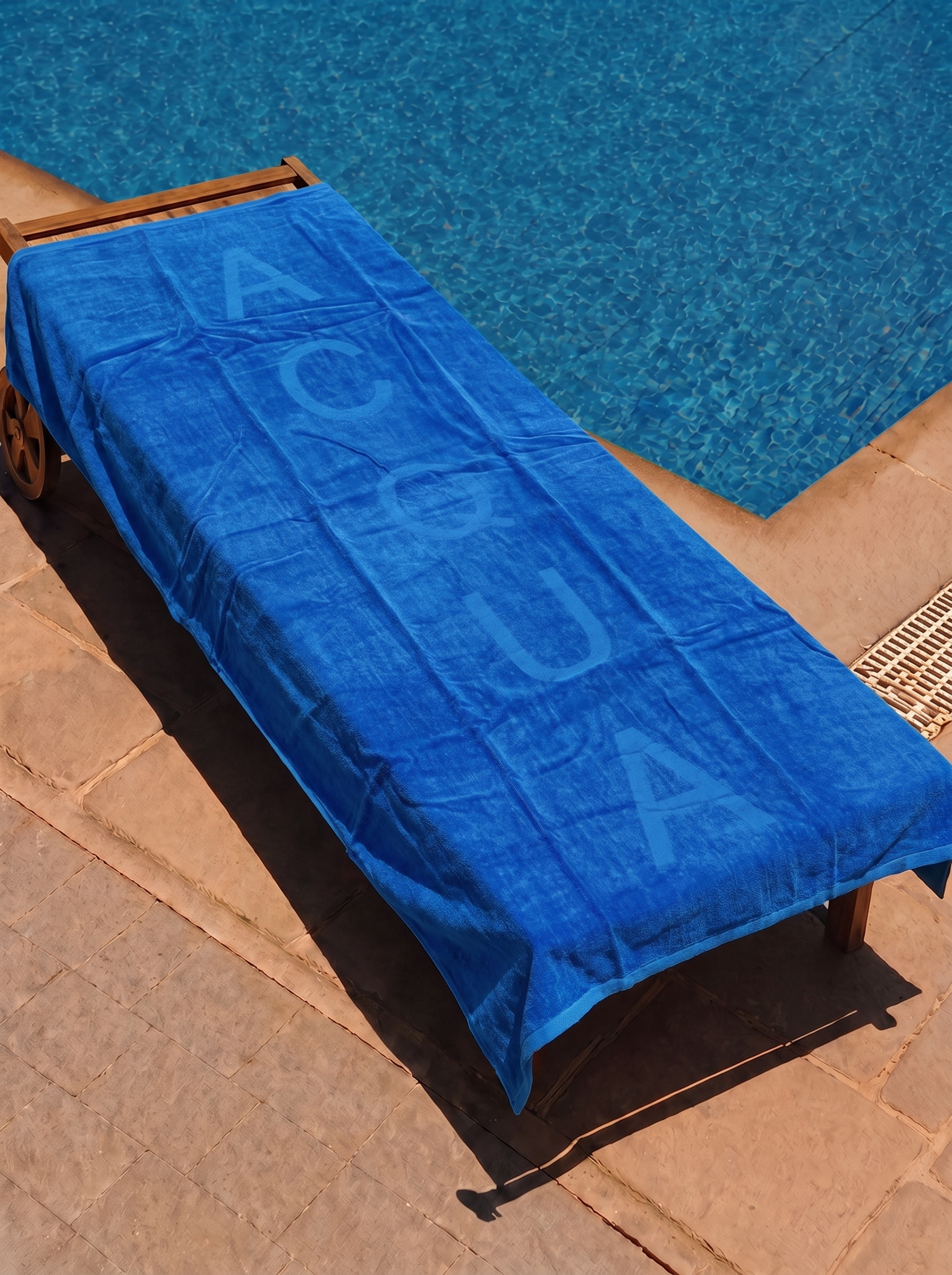Blue Acqua text towel on a poolside lounge chair