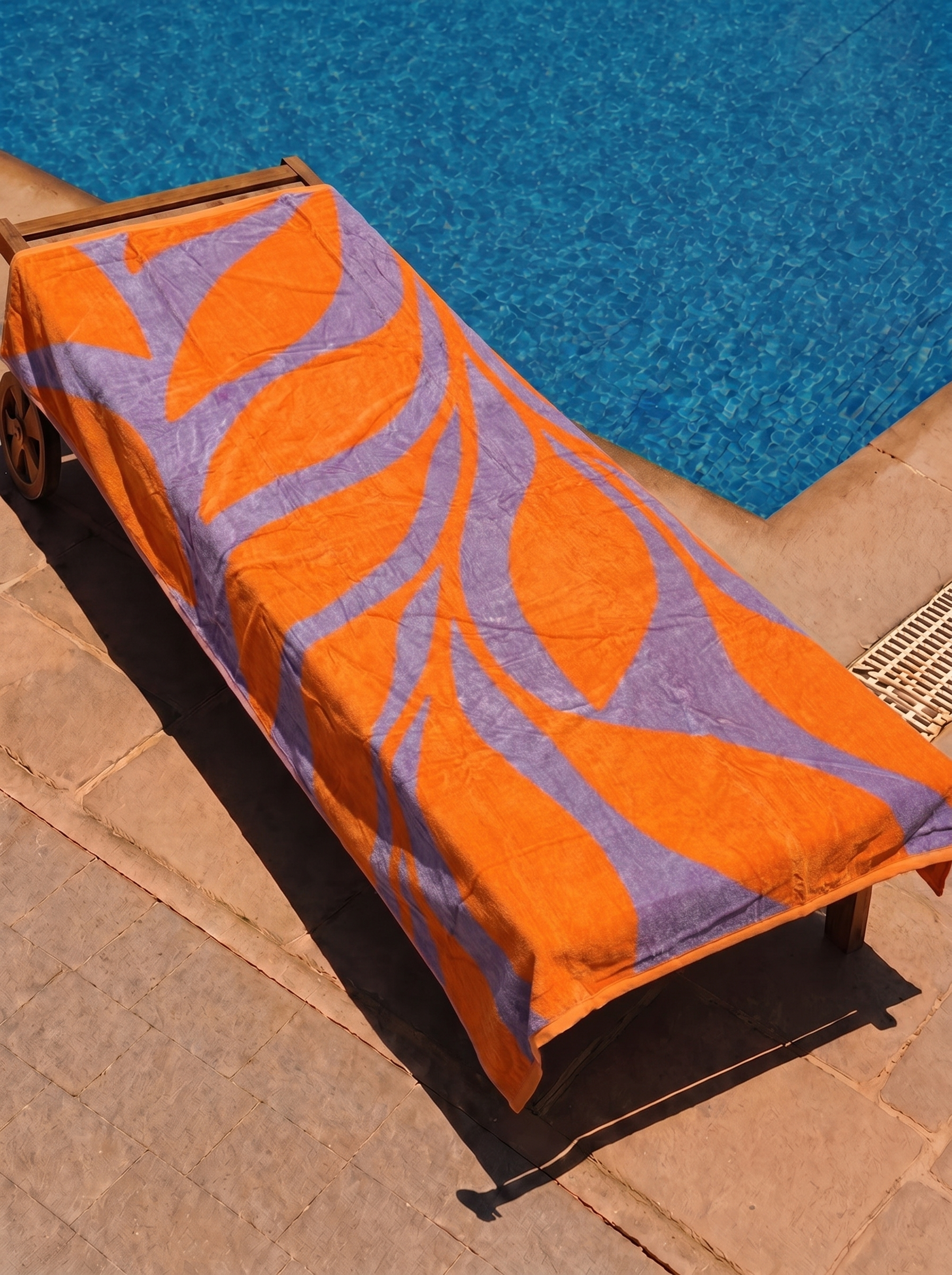 Orange and lavender leaf swirl towel on a poolside lounge chair