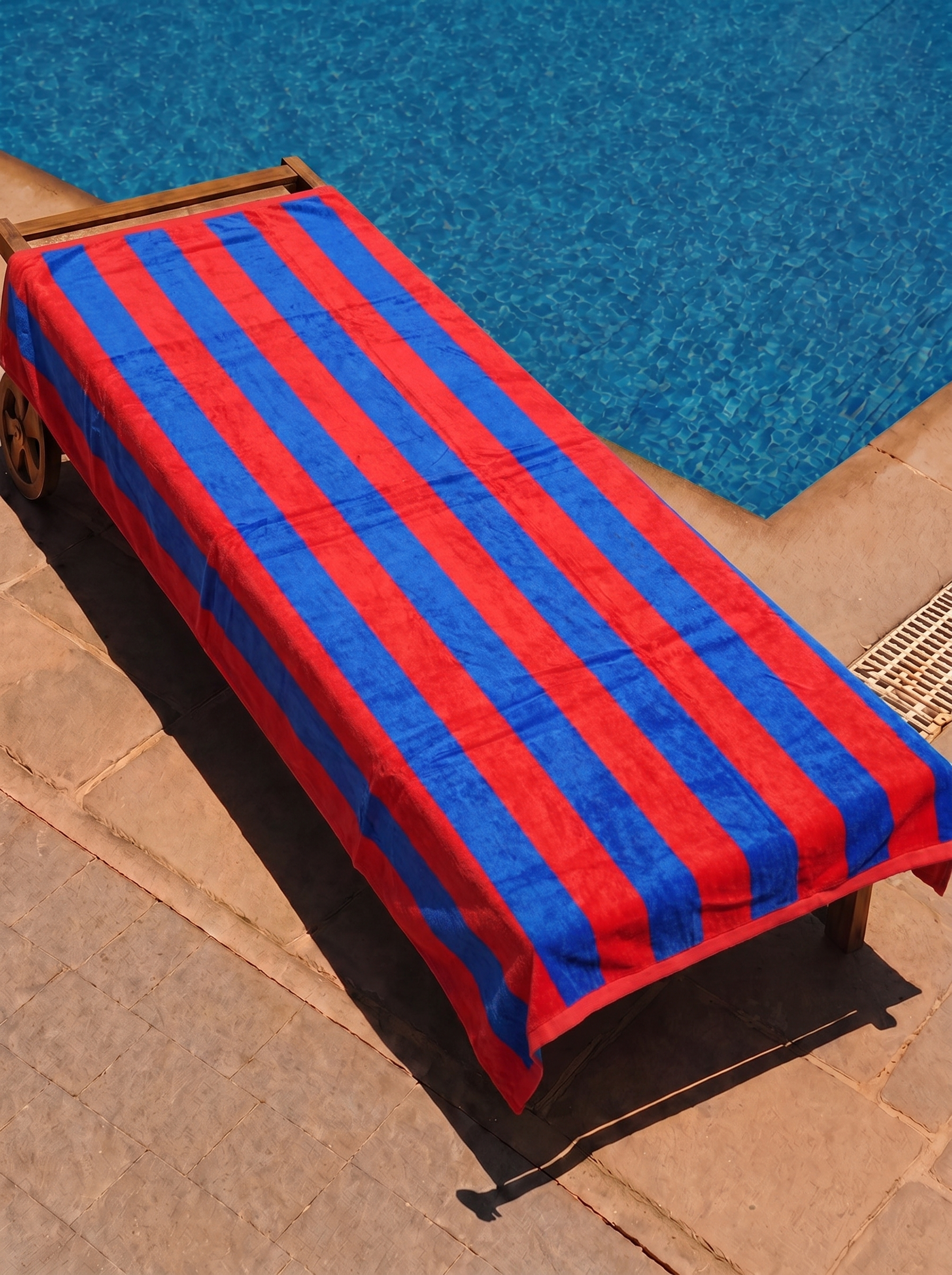 Red and blue cabana stripe towel on a poolside lounge chair