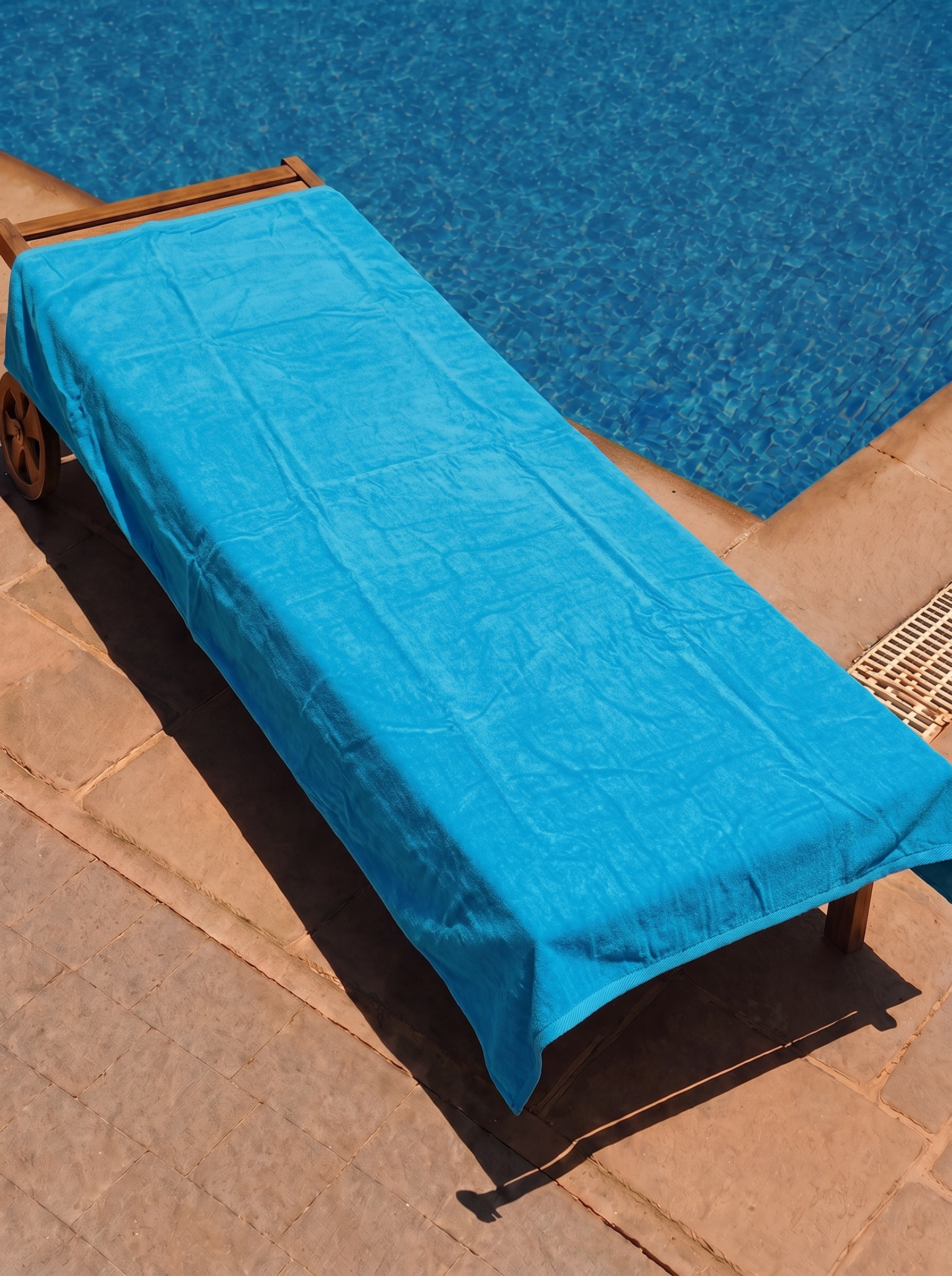 Solid turquoise towel on a poolside lounge chair