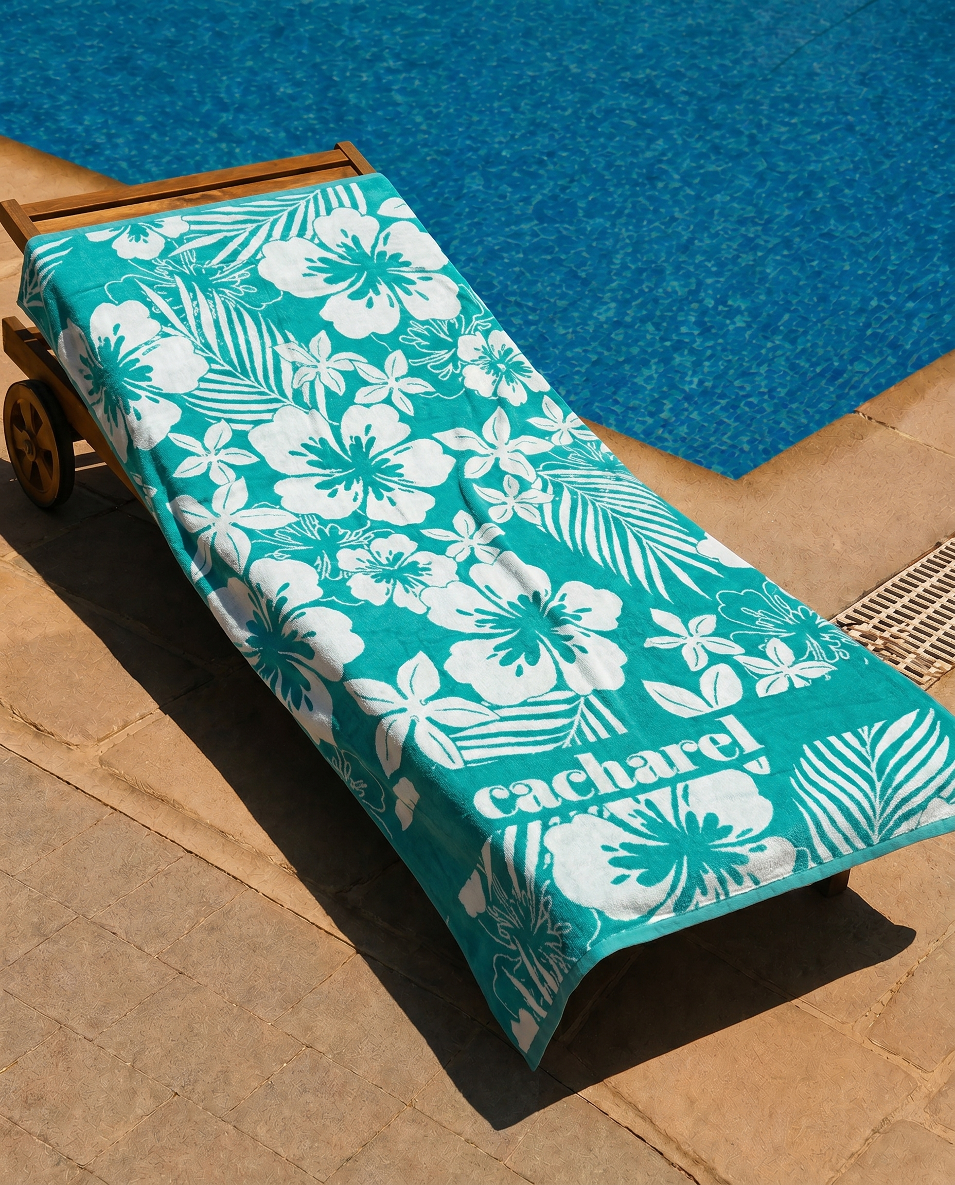 Teal Hibiscus Beach Towel draped on a lounge chair